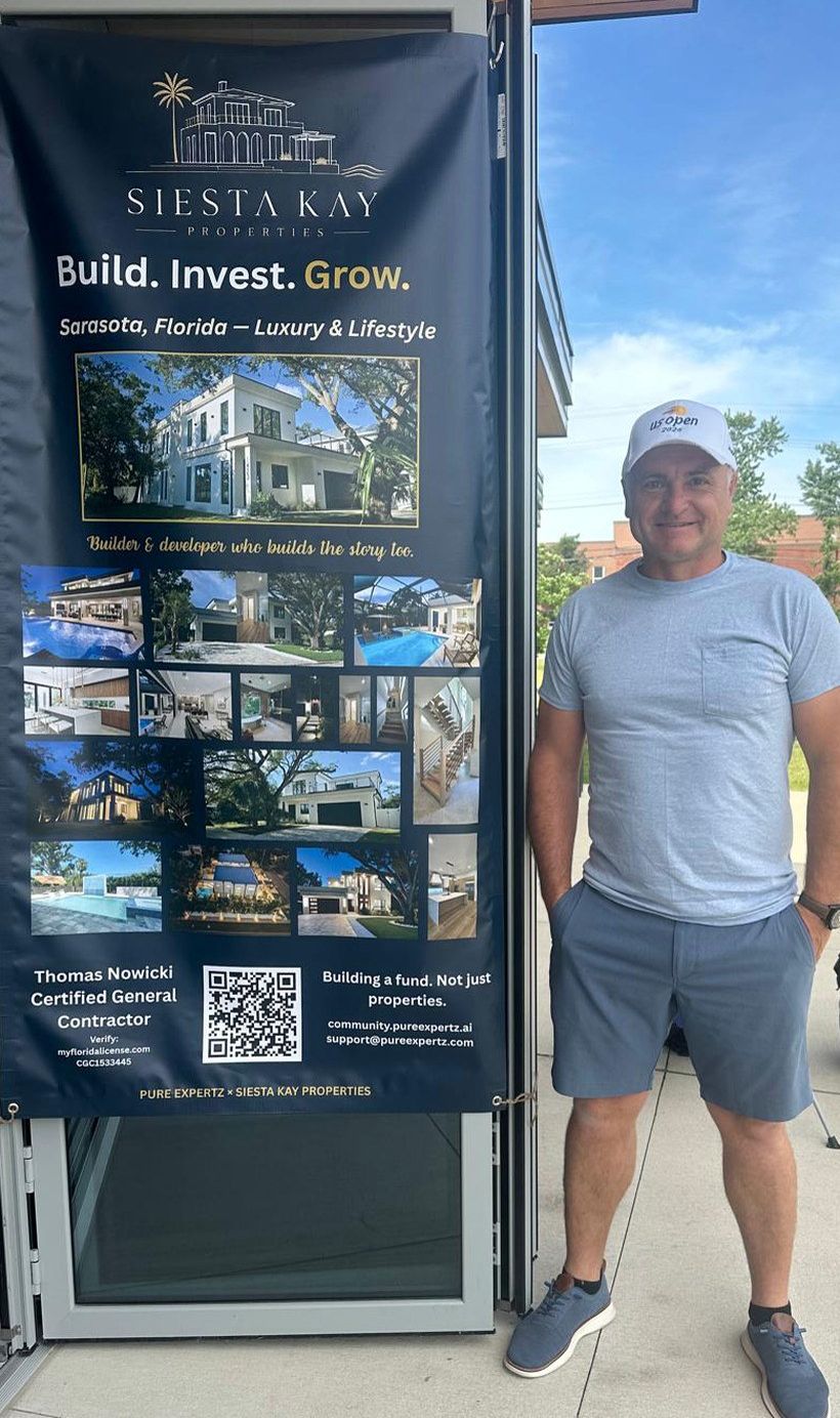 Thomas Nowicki standing beside the printed Siesta Kay Properties banner.